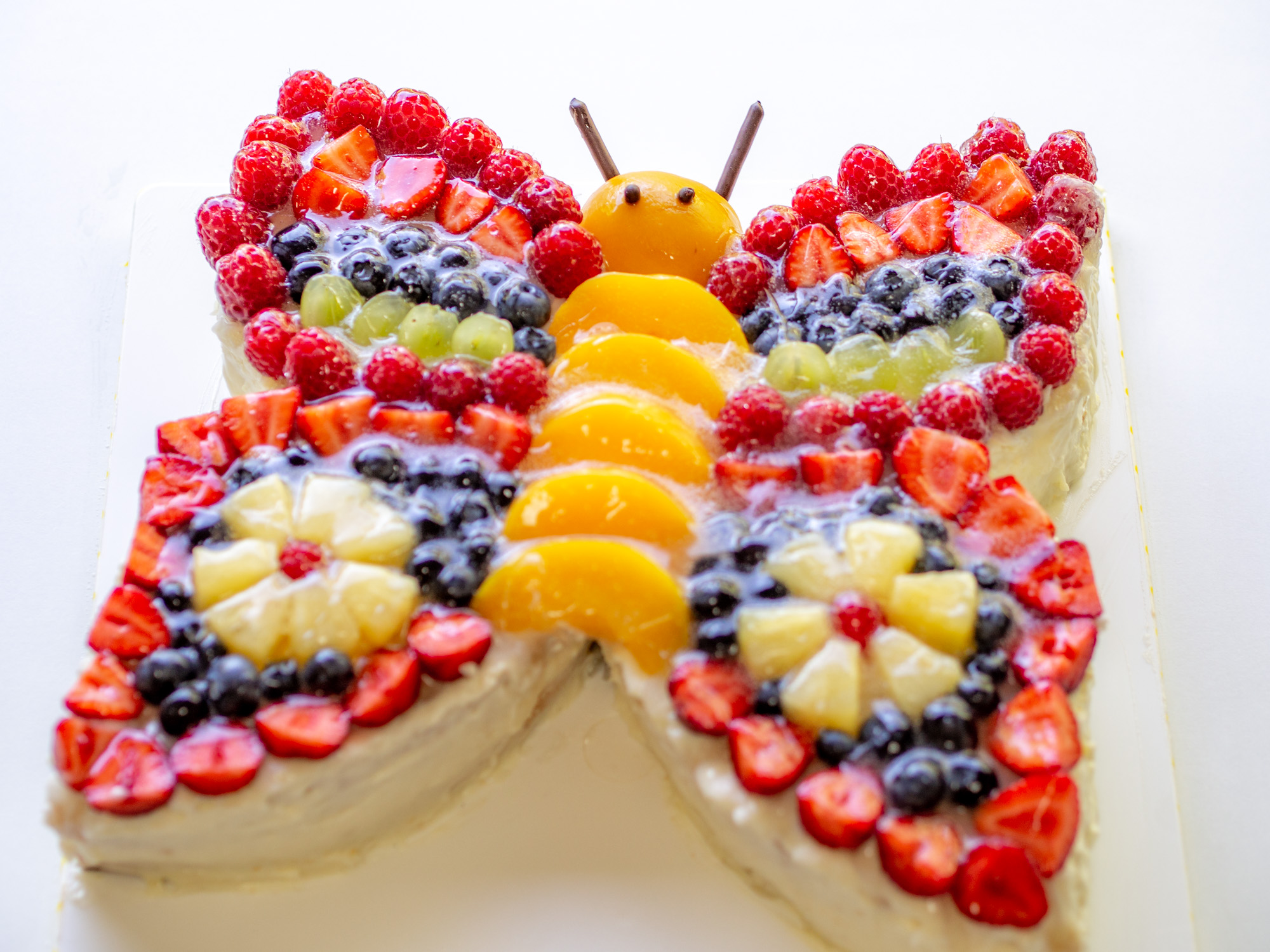 Bunter Schmetterlingstorte mit viel Obst dekoriert - perfekt für Kinder